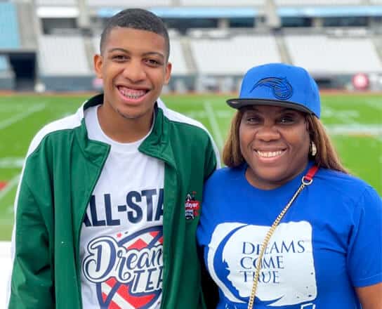 A male Dreamer posing with his parent on the Jacksonville Jaguars field.
