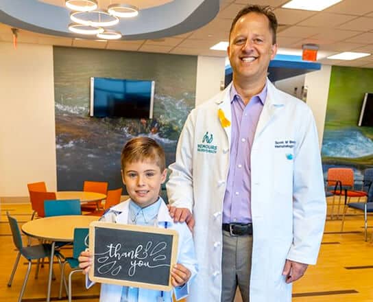 A doctor posing with a male Dreamer holding a Thank You sign.