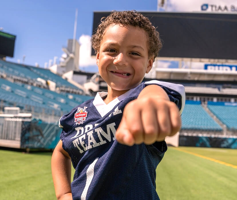 A Dreamer smiling and pointing his fist towards the camera lens on the Jacksonville Jaguars football field.