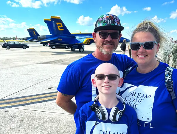 A family with their son posing on an airfield with the Blue Angels aircraft